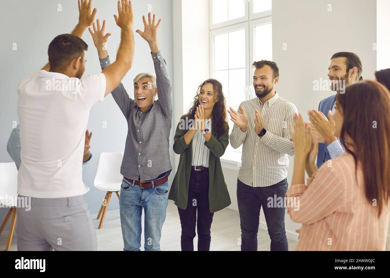 Deux hommes d'affaires heureux se donnent un double cinq aux applaudissements de leurs collègues. Banque D'Images