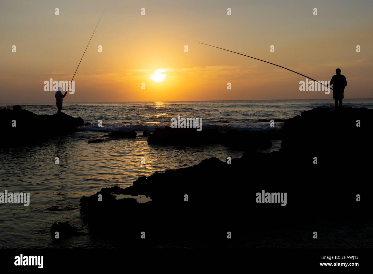 Deux pêcheurs profitant de la dernière lumière du soleil à la plage en Israël Banque D'Images