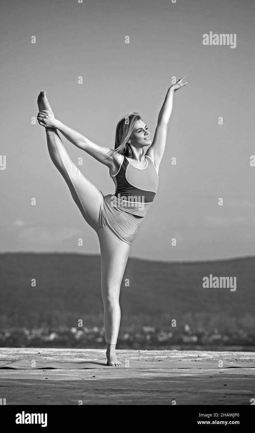 Jeune femme de fitness faisant des exercices d'étirement pour les jambes sur fond de ciel. Banque D'Images
