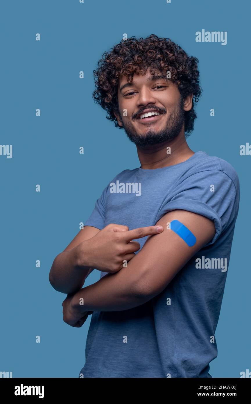 Homme souriant montrant le plâtre sur son bras supérieur Banque D'Images