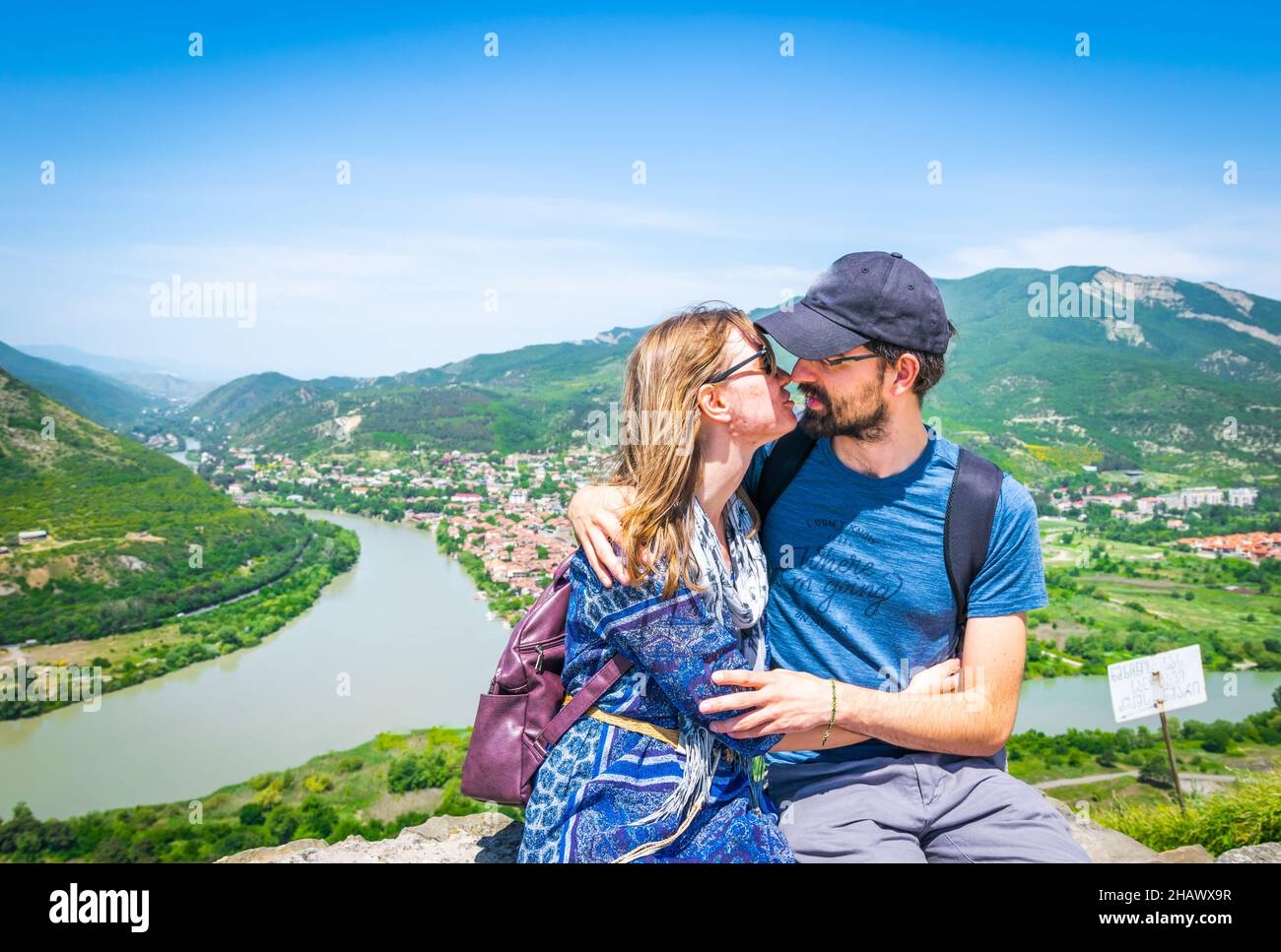 Le couple s'assoit et s'embrasse avec une vue panoramique sur les montagnes et le fond de la ville de Mtskheta et pose pour une photo de voyage.Excursion à summ Banque D'Images
