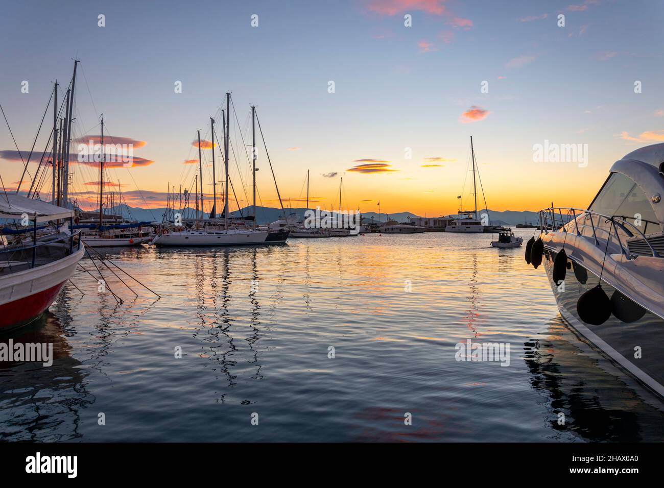 Bateaux de pêche, voiliers et yachts en début de soirée coucher de soleil le long du port et de la marina en face du village de pêche grec d'Aegina, Grèce, l'un des Banque D'Images