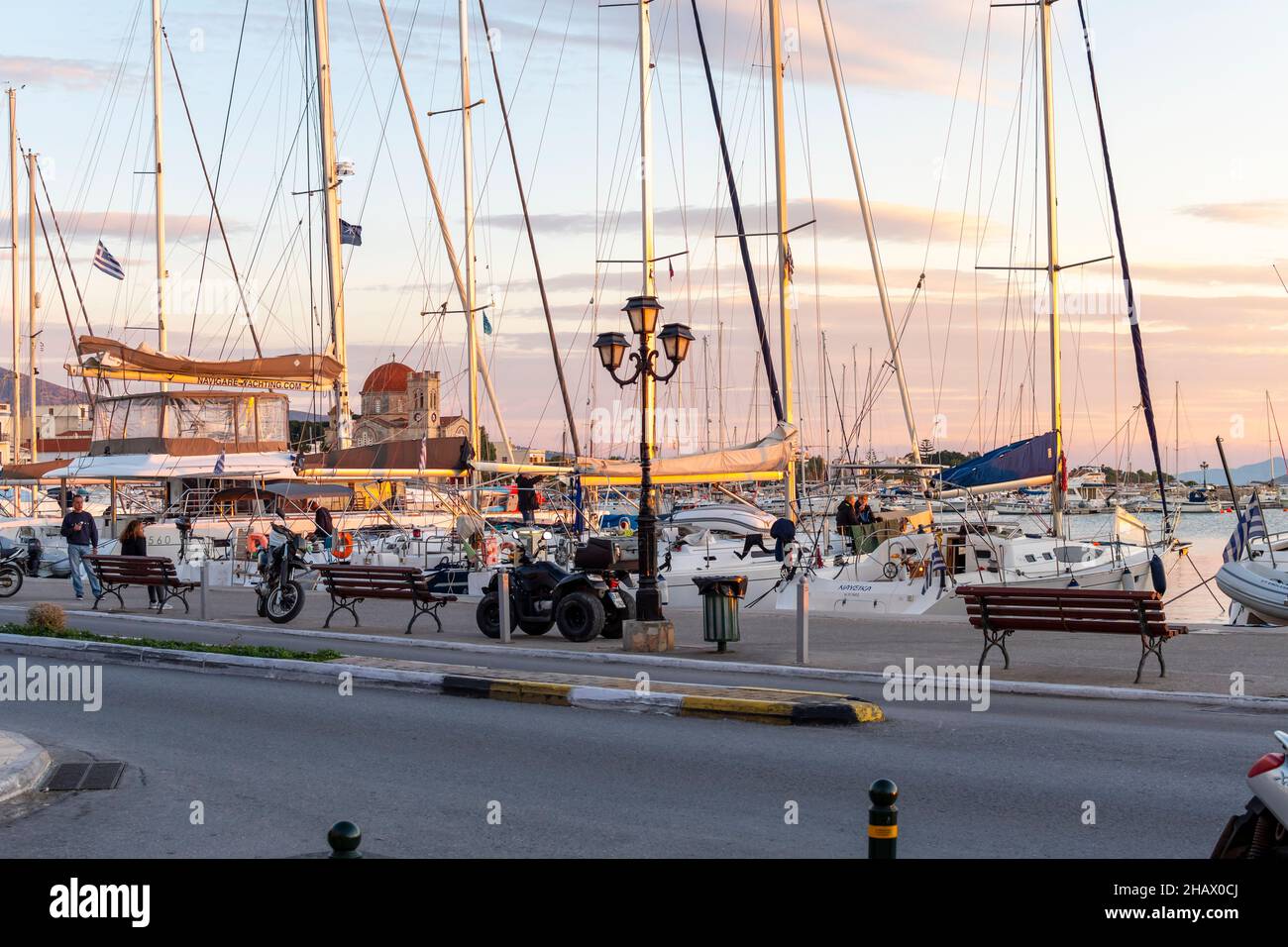 Bateaux de pêche, voiliers et yachts en début de soirée coucher de soleil le long du port et de la marina en face du village de pêche grec d'Aegina, Grèce, l'un des Banque D'Images