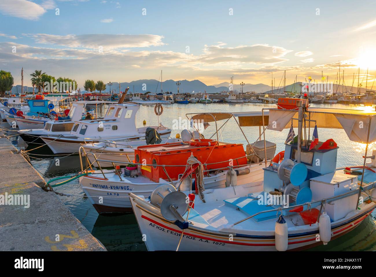 Des bateaux de pêche colorés bordent le port de l'île grecque d'Aegina, Grèce au crépuscule, avec la promenade du front de mer en vue. Banque D'Images
