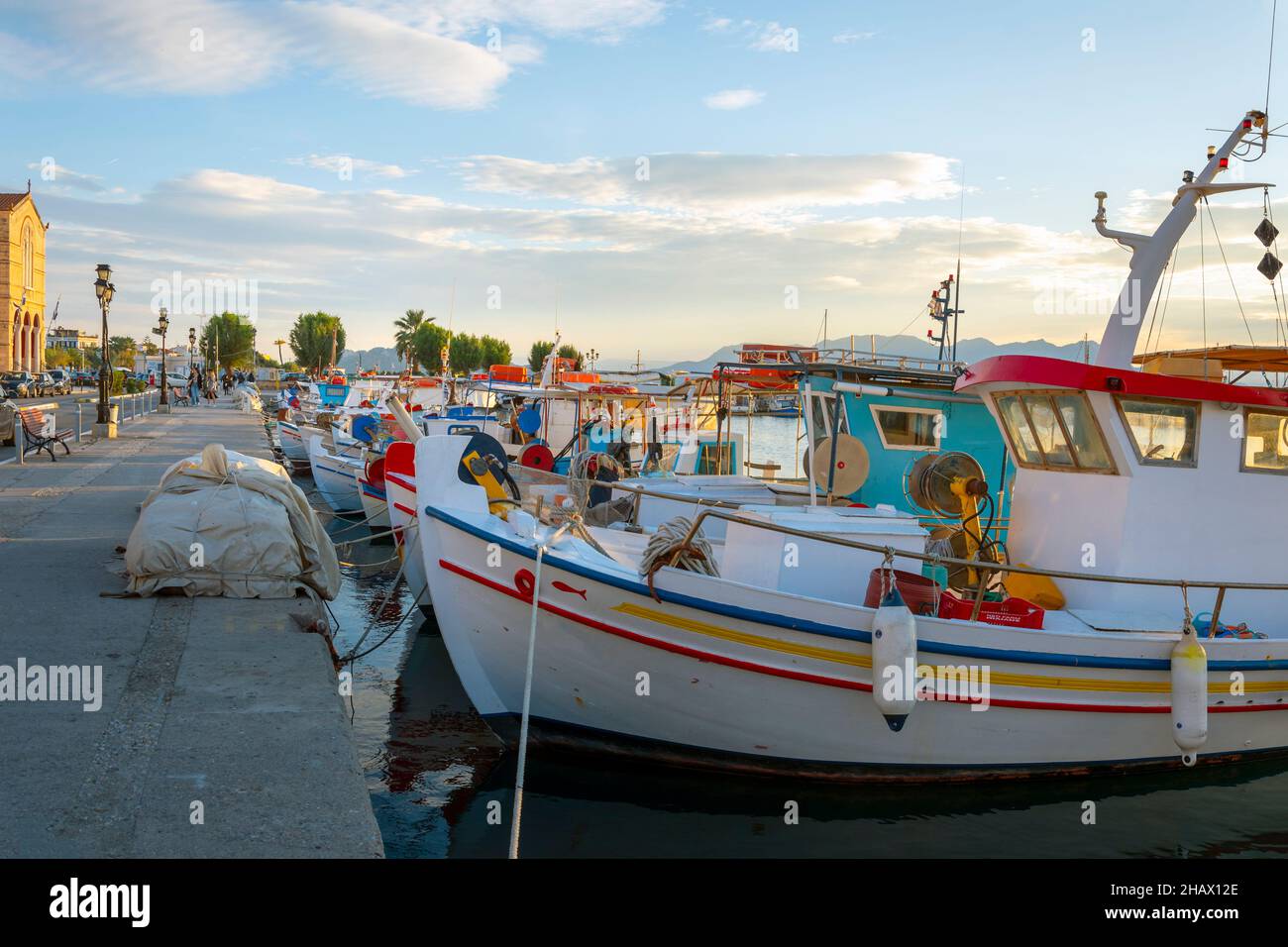 Des bateaux de pêche colorés bordent le port de l'île grecque d'Aegina, Grèce au crépuscule, avec la promenade du front de mer en vue. Banque D'Images