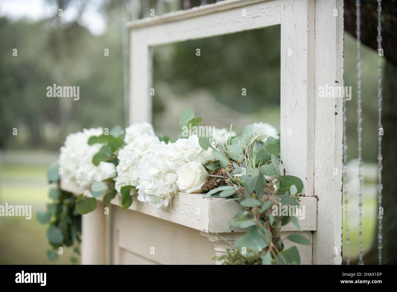 Cheminée avec miroir, roses blanches et feuilles vertes lors de la cérémonie de mariage des otdoes Banque D'Images Cheminée avec miroir, roses blanches et feuilles vertes lors de la cérémonie de mariage des otdoes Banque D'Images