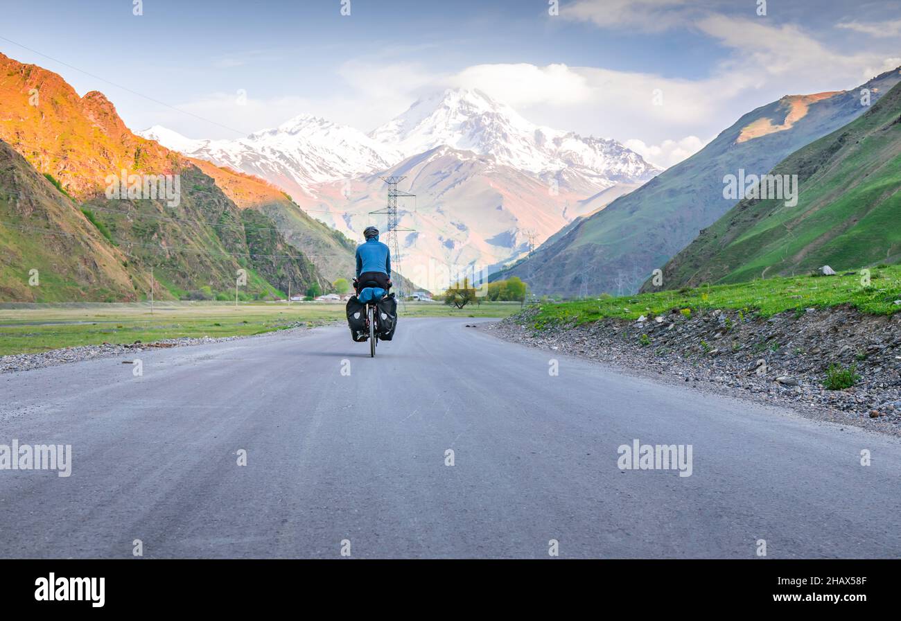 Homme en blouson bleu vélo avec vélo de randonnée surfé par les montagnes et la nture d'été verte.TOU autour du parc national de kazbegi. Banque D'Images