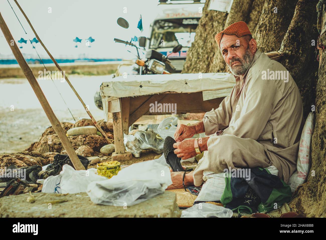 Ancien homme d'Asie du Sud assis dans une rue et fixant des chaussures Banque D'Images