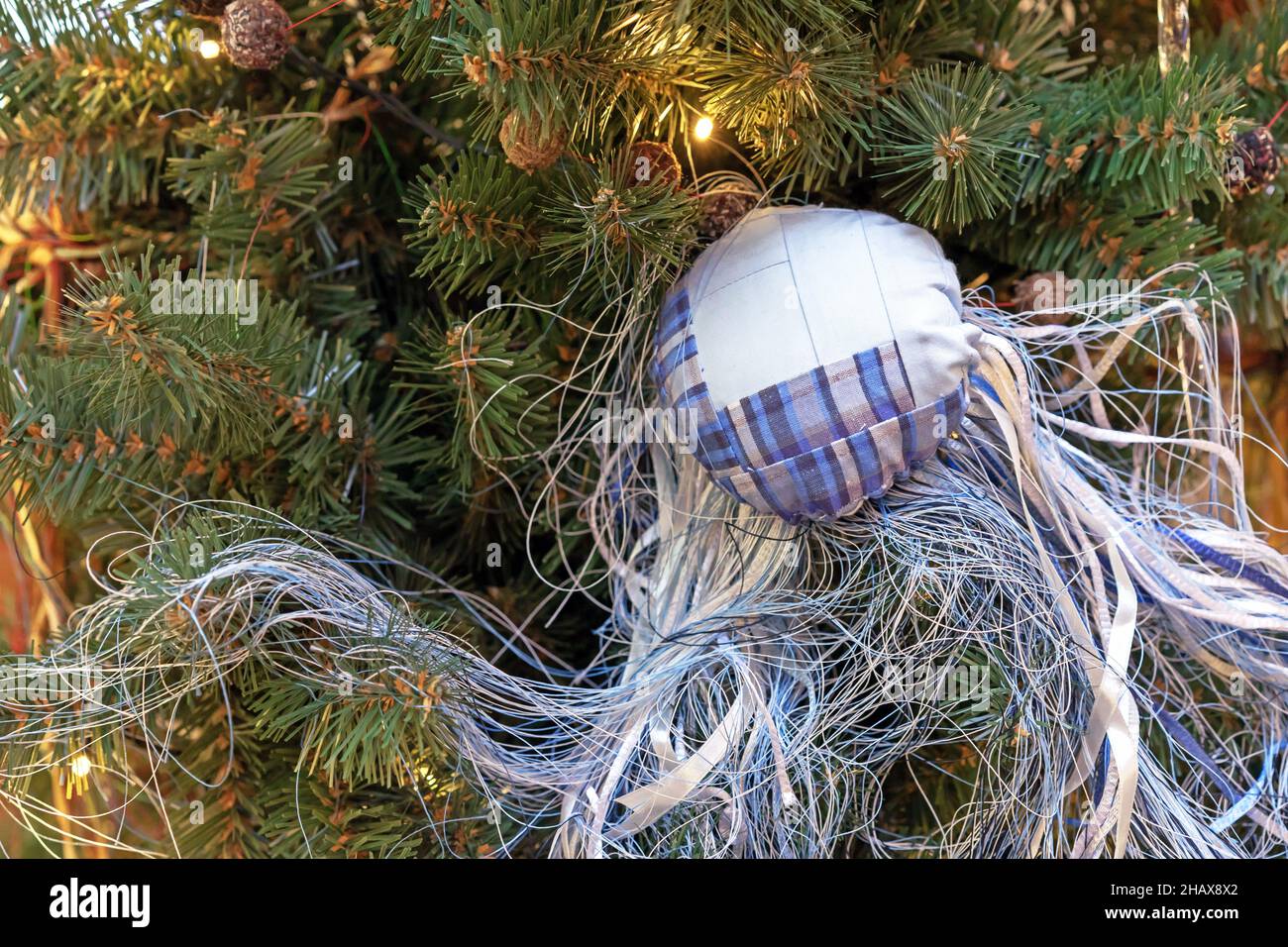 Boule de Noël en tissu avec de nombreux fils est suspendue sur un arbre de  Noël avec une guirlande Photo Stock - Alamy