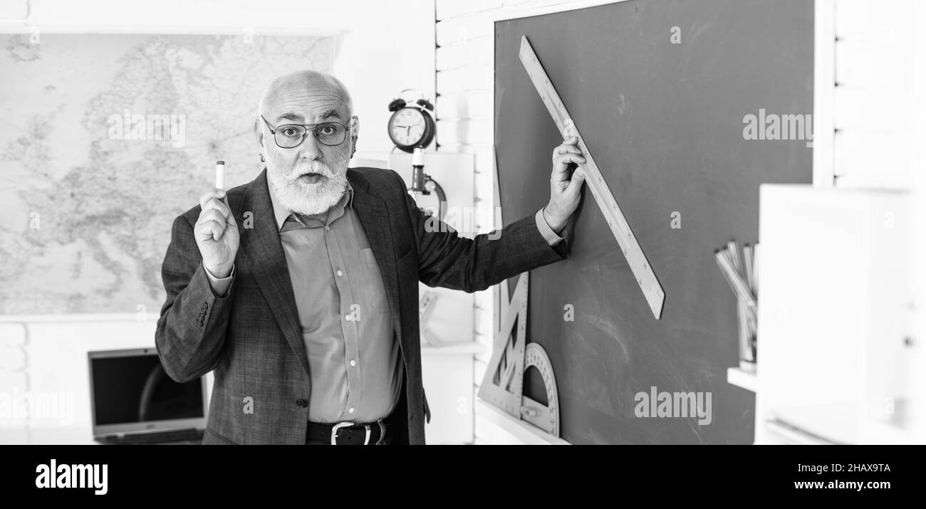 bonne idée. école secondaire éducation moderne. professeur d'homme senior utiliser la règle pendant le dessin. professeur d'homme en lunettes dessiner avec la règle sur le tableau noir. retour à Banque D'Images