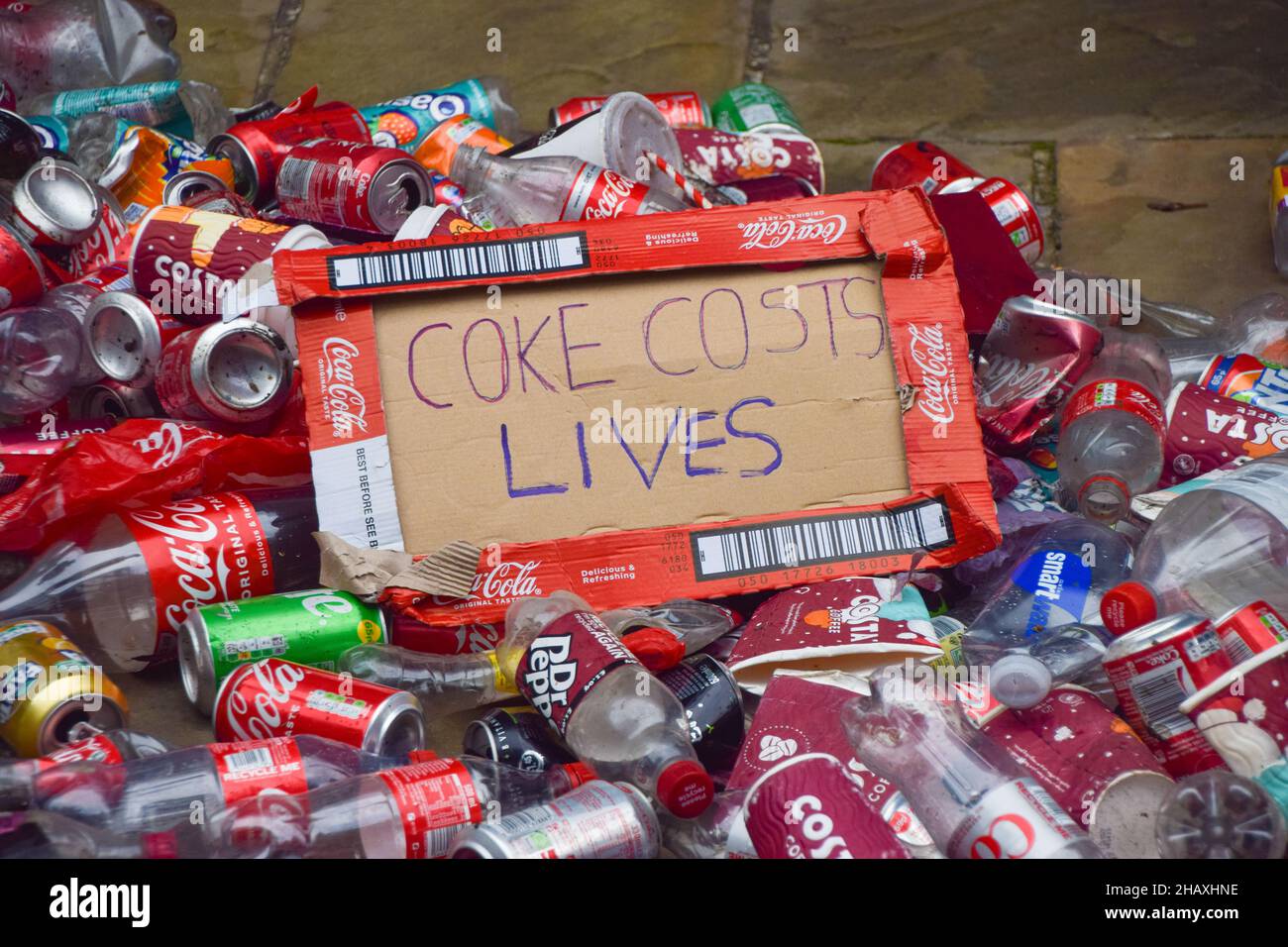 Londres, Royaume-Uni.15th décembre 2021.L'étiquette « Coke Ces Costs Lives », constituée d'une boîte à coke, est visible parmi les bouteilles en plastique et les boîtes en étain au cours de la démonstration.extinction les activistes de la rébellion ont déversé des bouteilles en plastique et des boîtes en étain à l'extérieur du siège des partenaires européens de Coca-Cola à Uxbridge.En plus de la pollution mondiale, les activistes accusent le géant des boissons gazeuses de manipulation, de violations des droits de l'homme et de cupidité d'entreprise.Crédit : SOPA Images Limited/Alamy Live News Banque D'Images