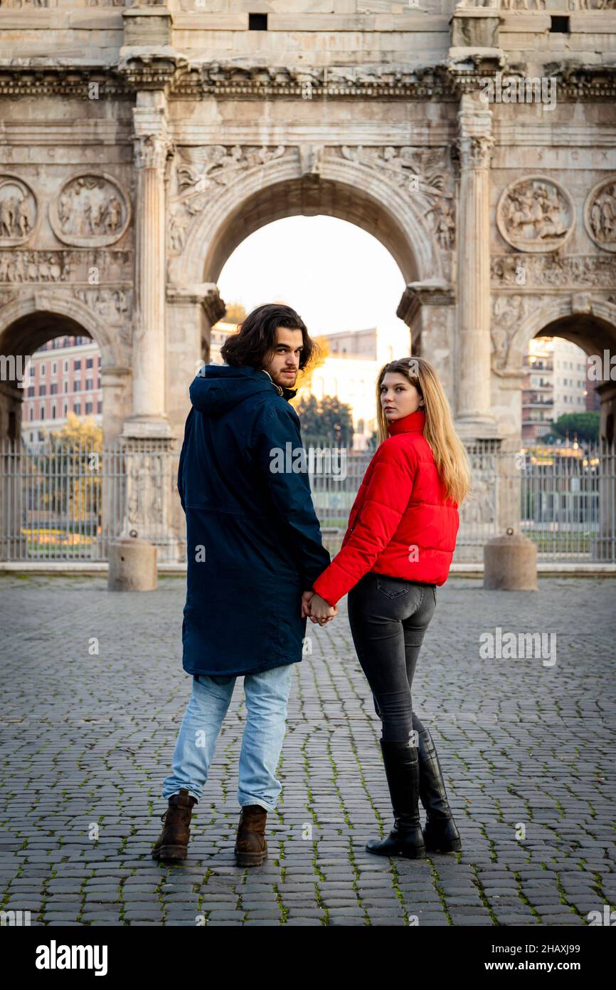 Jeune couple en voyage à Rome.Le jeune couple tient les mains et se déplace devant l'Arche de Titus. Banque D'Images