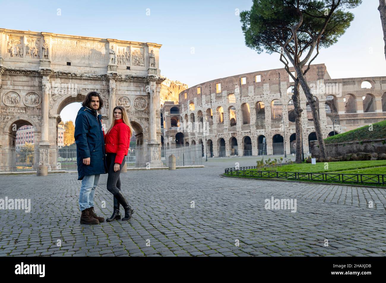 Jeune couple en voyage à Rome.Le jeune couple pose devant l'Arche de Titus.La blonde dans sa veste rouge met sa main sur son boyfrien Banque D'Images