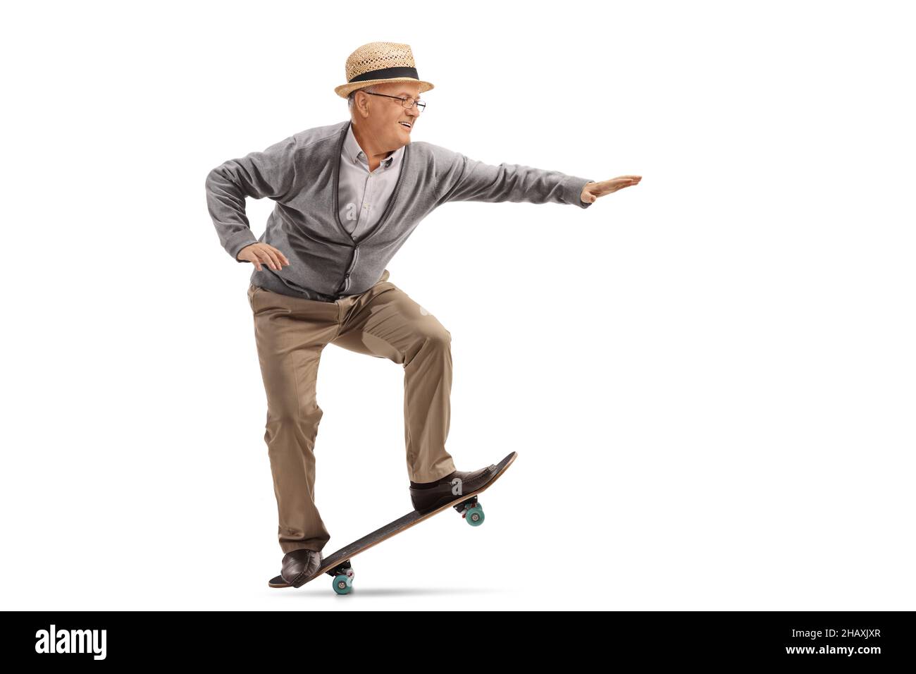 Photo de profil sur toute la longueur d'un homme âgé qui réalise un tour sur un skateboard isolé sur fond blanc Banque D'Images