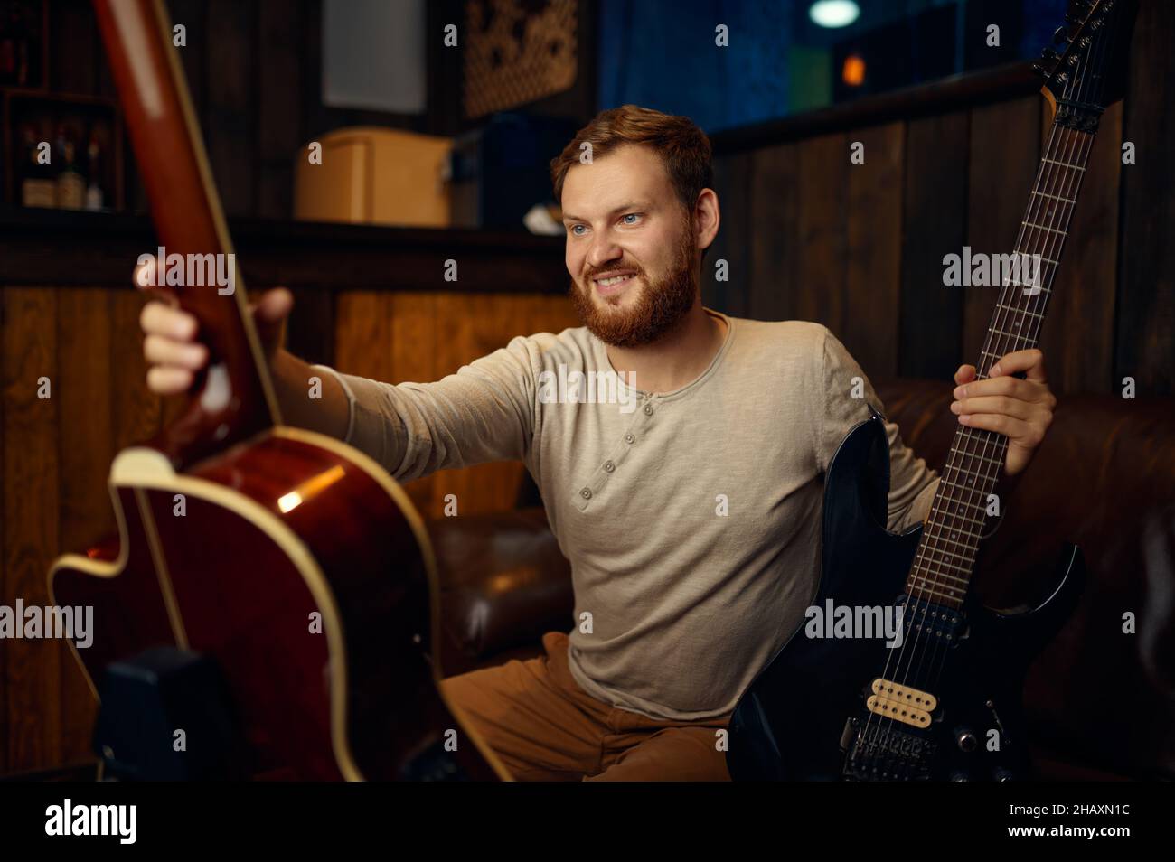 Jeune guitariste qui choisit la guitare électrique ou acoustique Banque D'Images