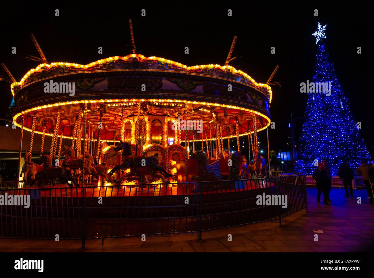 Bournemouth, Dorset, Royaume-Uni. 15 décembre 2021. Les visiteurs, les familles et les enfants enthousiastes affluent dans les jardins de Bournemouth par une douce soirée pour découvrir le pays des merveilles de l'arbre de Noël de Bournemouth avec plus de 100 arbres scintillants et illuminations. Certains des arbres sont thématiques pour représenter six villes à travers le monde. Les visiteurs peuvent suivre le sentier. Carrousel de chevaux au galop, joyeuse ronde à Pier Approach. Crédit : Carolyn Jenkins/Alamy Live News Banque D'Images
