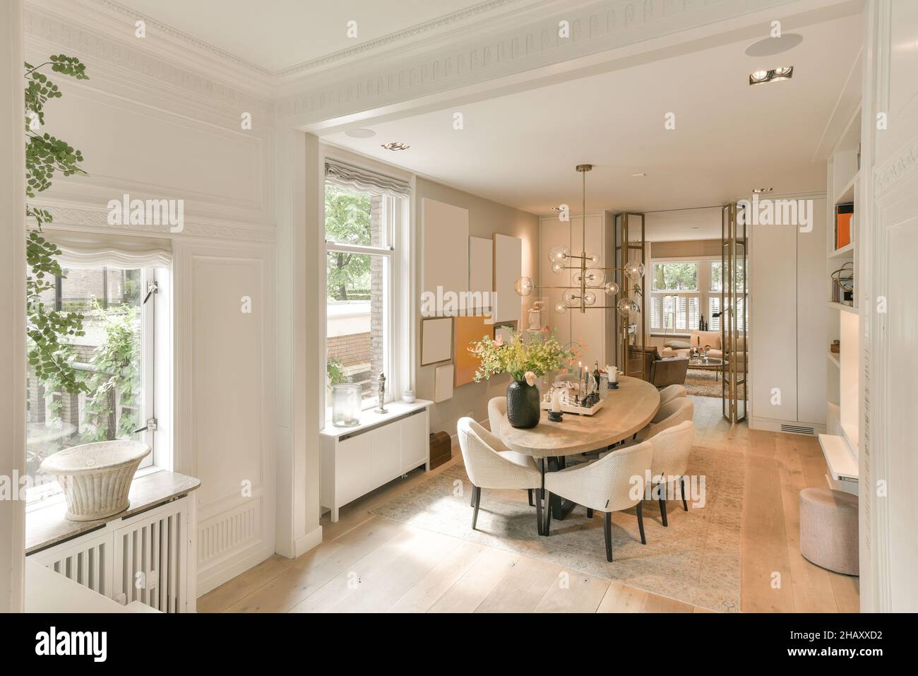 Intérieur moderne et spacieux salon avec table ovale pour les repas avec vase avec bouquet entouré de chaises douces et lustre lumineux Banque D'Images