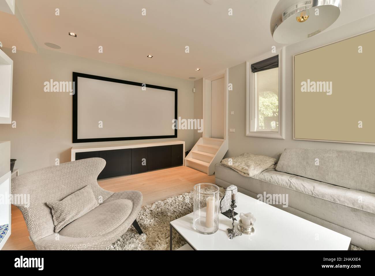Intérieur d'un salon élégant avec canapé confortable et fauteuil table basse avec éléments décoratifs et écran de projection sur le mur Banque D'Images