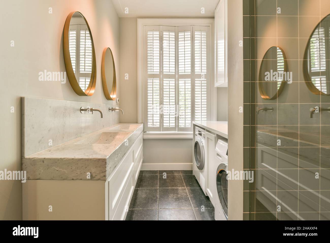 Lave-linge et sèche-linge blancs placés près d'un lavabo avec miroirs dans  la salle de bains lumineuse de l'appartement Photo Stock - Alamy