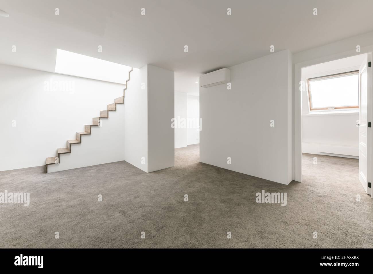 Intérieur de l'espace vide spacieux sous-sol dans la maison avec murs blancs et plancher gris et système de suspension et escalier menant à l'étage supérieur Banque D'Images