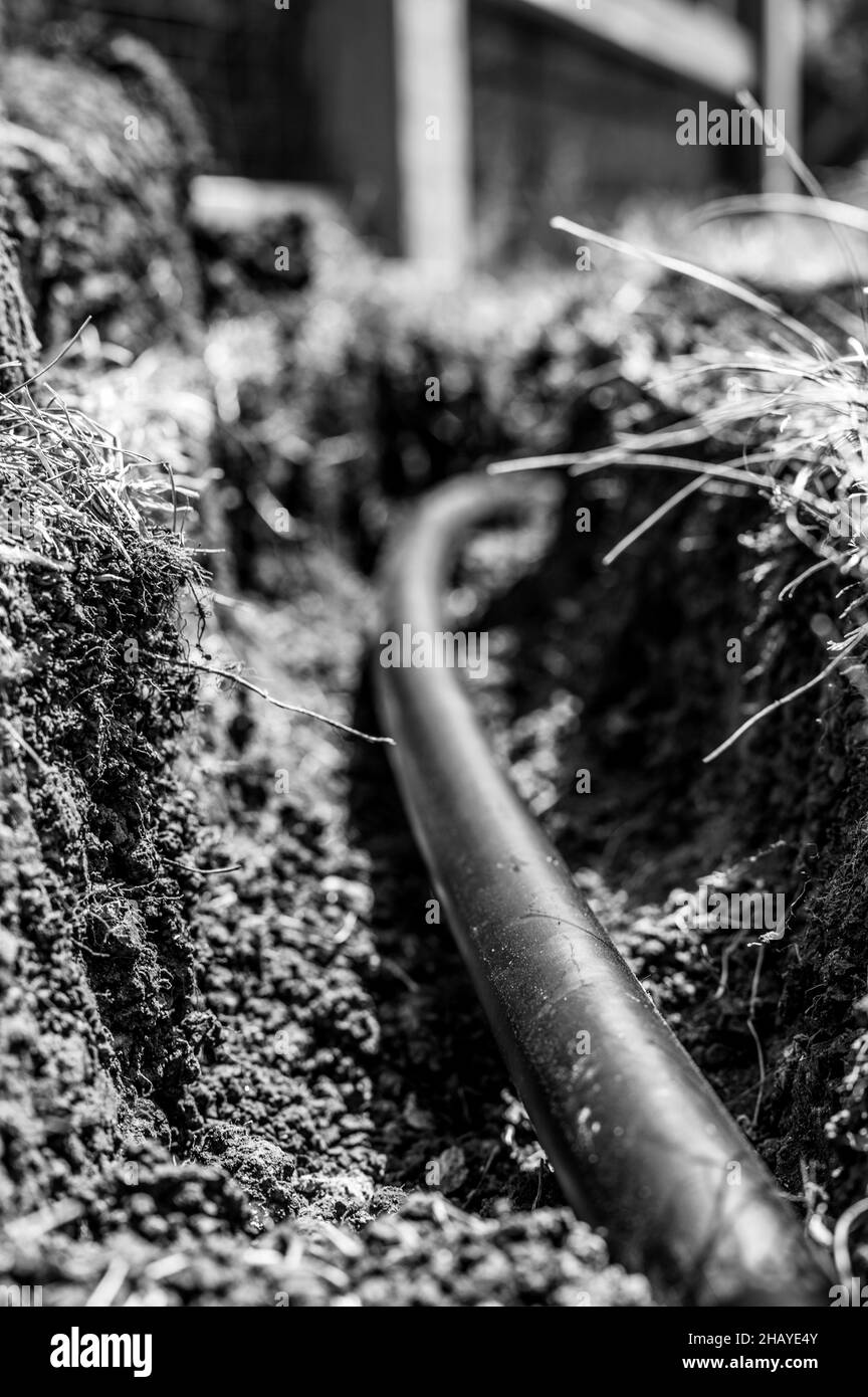 Concentrez-vous sur une ligne d'eau en plastique noire de 1 pouce posée dans une tranchée peu profonde Banque D'Images
