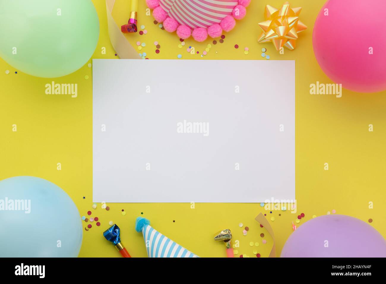 Fond joyeux anniversaire, plat lay coloré décoration de fête avec carte d'invitation de circulaire sur fond jaune pastel. Banque D'Images Fond joyeux anniversaire, plat lay coloré décoration de fête avec carte d'invitation de circulaire sur fond jaune pastel. Banque D'Images