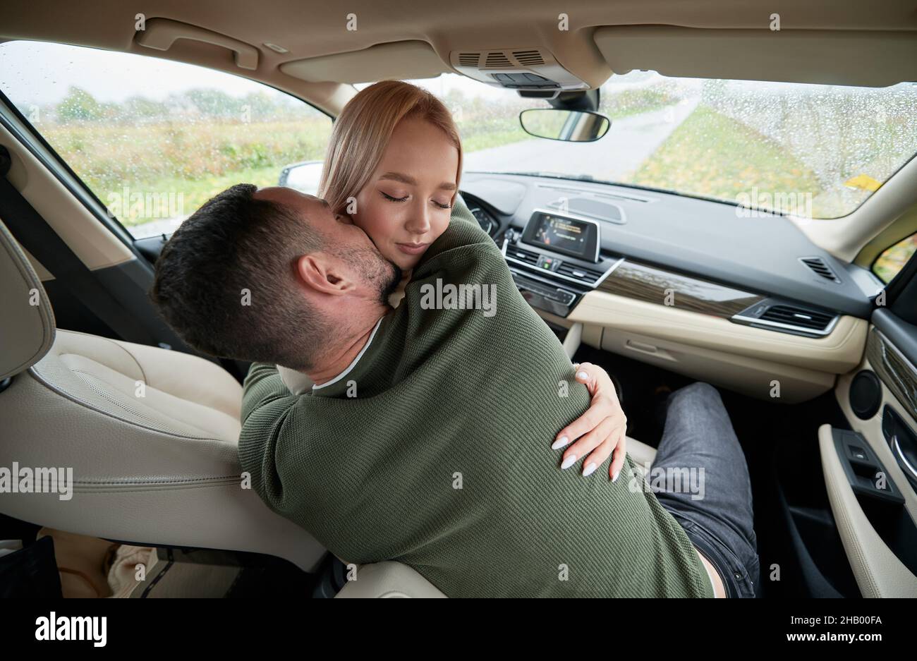Vue rapprochee d un couple qui s embrasse les uns les autres lorsqu il est assis sur les sieges avant en mode automatique.Homme embrassant son bien aime pendant la detente en voiture.Femme assise sur ...