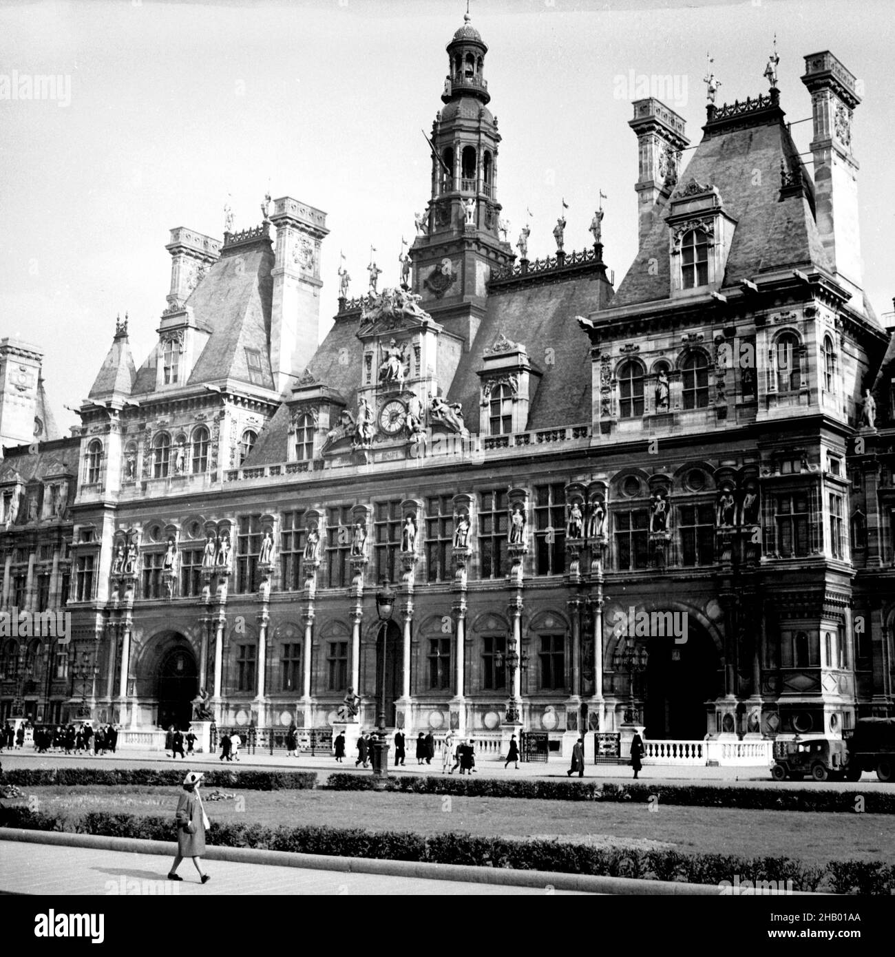 Paris Hôtel de ville, 1945.Une photographie du centre de la façade du bâtiment.Une femme marche à travers la vue de premier plan de la structure historique tandis que des dizaines de personnes sont représentées dans l'arrière-plan plus près du bâtiment.Sept mois seulement avant la prise de cette photo, le général Charles de Gaulle se tenait à la fenêtre pendant la libération et fit un discours émouvant. Banque D'Images
