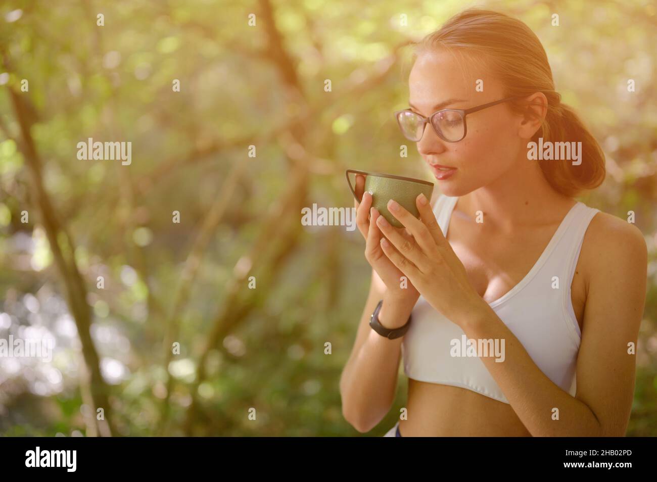 belle jeune femme en verres boire du thé de la tasse dans le parc Banque D'Images