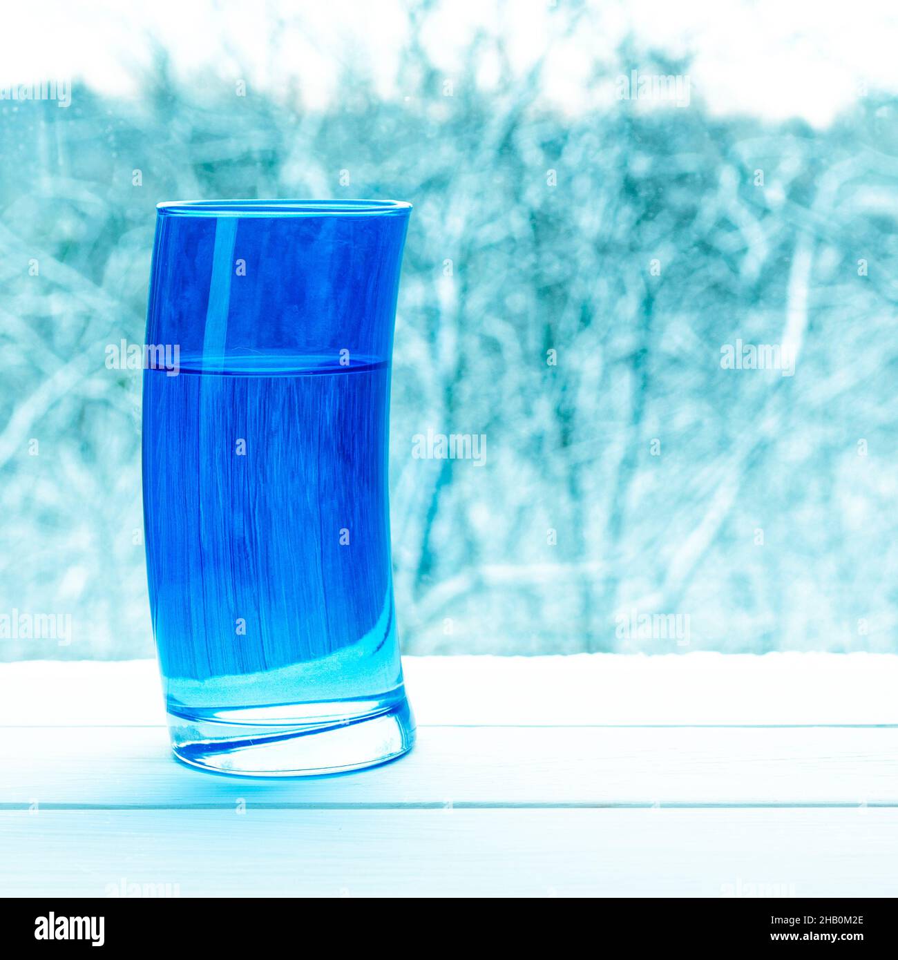 Verre bleu déformé avec eau de source claire sur le fond d'une forêt  enneigée Photo Stock - Alamy