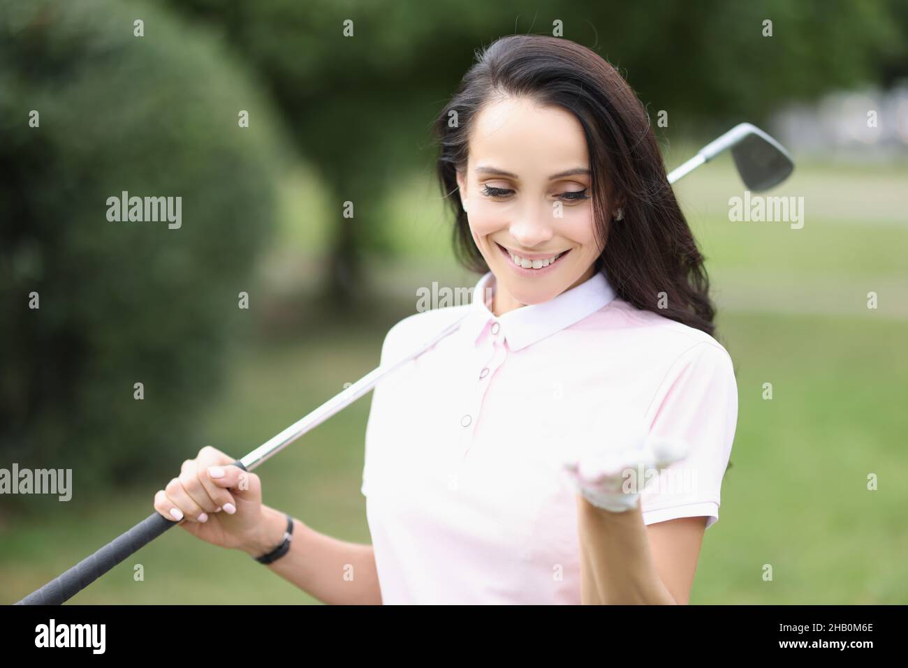Souriante professionnelle de joueur de golf femme tenir le ballon sur la paume Banque D'Images