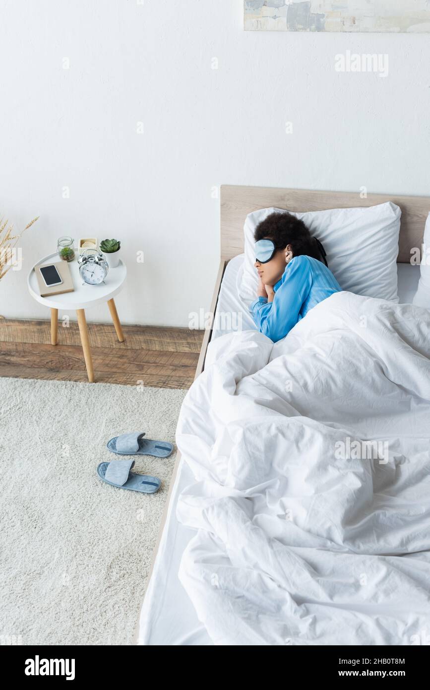vue en grand angle de la femme afro-américaine dans un masque oculaire dormant au lit Banque D'Images