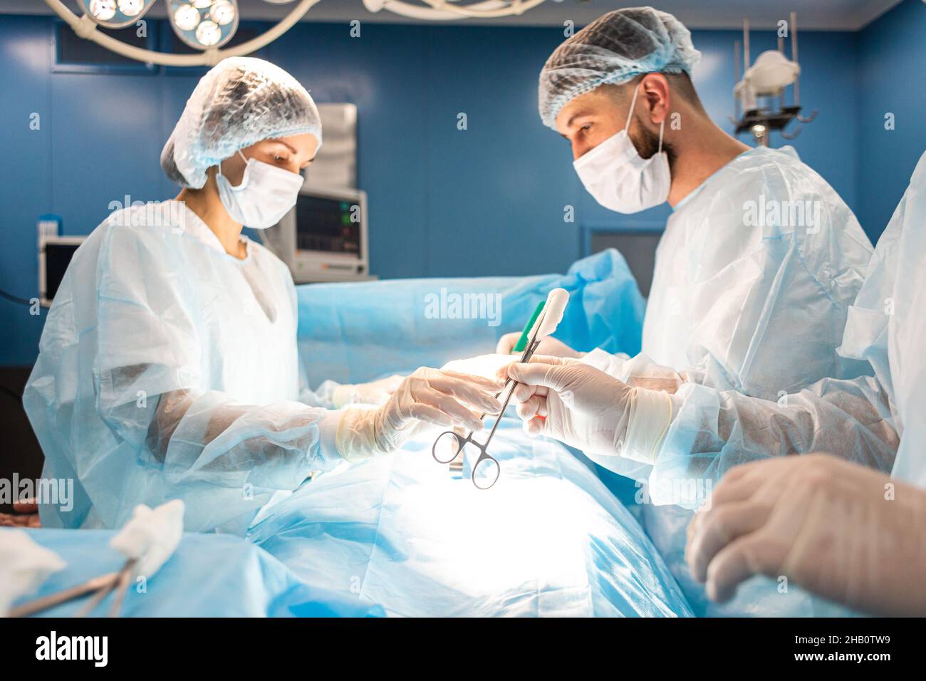 Une équipe internationale de médecins effectue une opération chirurgicale complexe sur un patient sous anesthésie. Salle d'opération moderne et chirurgiens expérimentés Banque D'Images