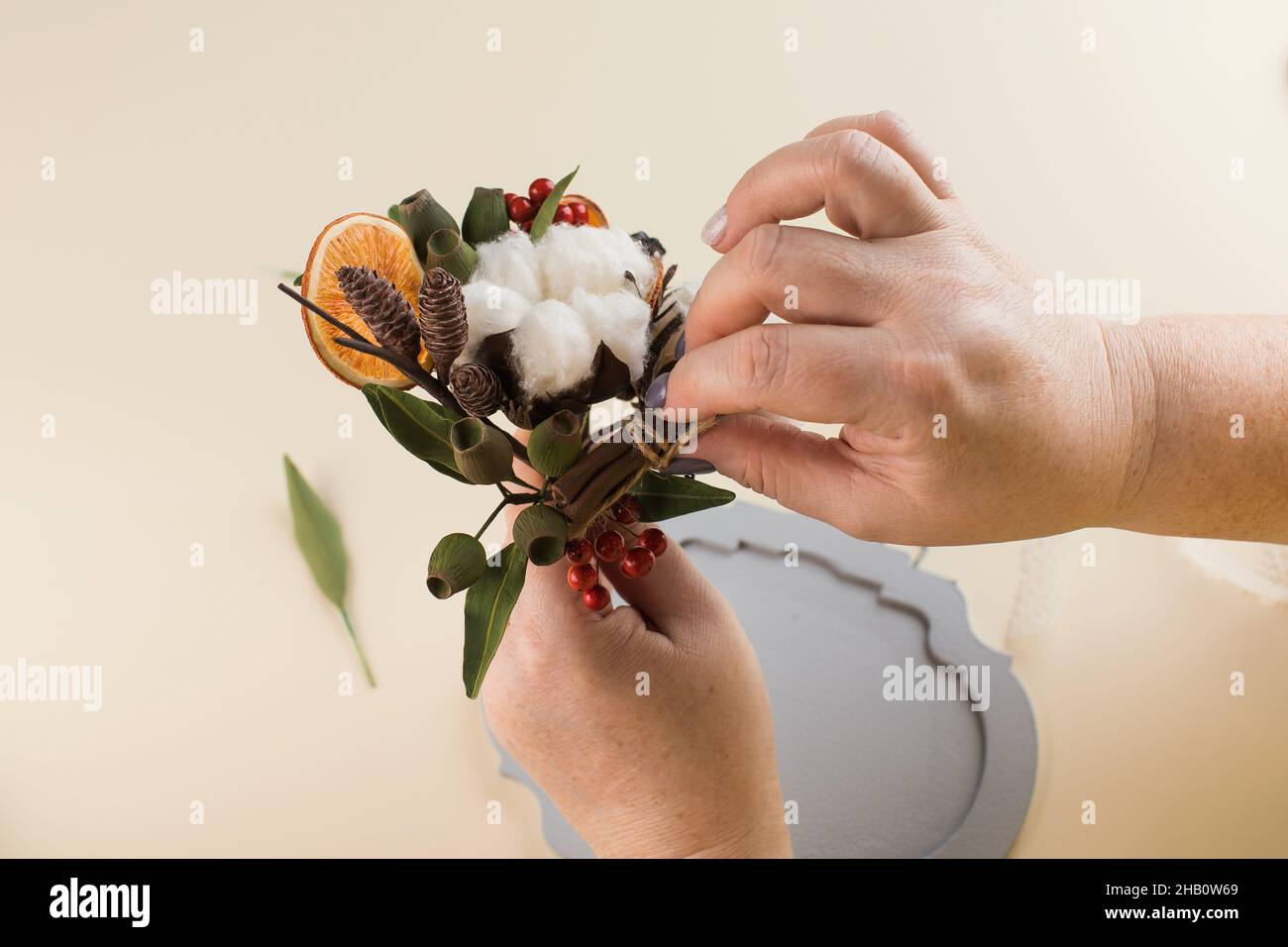 Femme tient un petit bouquet de fleurs de coton et des tranches d'orange  sèches au-dessus de la table Photo Stock - Alamy