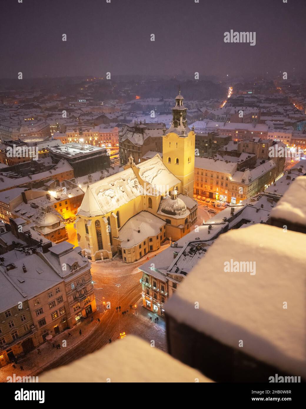Magnifique paysage urbain d'hiver Lviv avec des toits couverts de neige du sommet de l'hôtel de ville, Ukraine, Europe.Cathédrale latine illuminée par les lumières de la ville.Photographie de paysage Banque D'Images