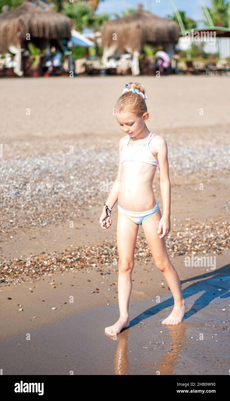 Petite fille dans un maillot de bain jouant sur la plage au bord de la mer  Photo Stock - Alamy