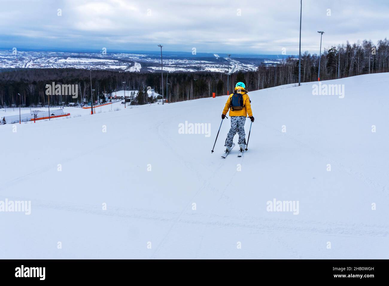 Jeune femme en blouson jaune et casque de ski ski ski ski sur une piste de montagne, sports d'hiver, ski alpin en plein air, vie active saine Banque D'Images