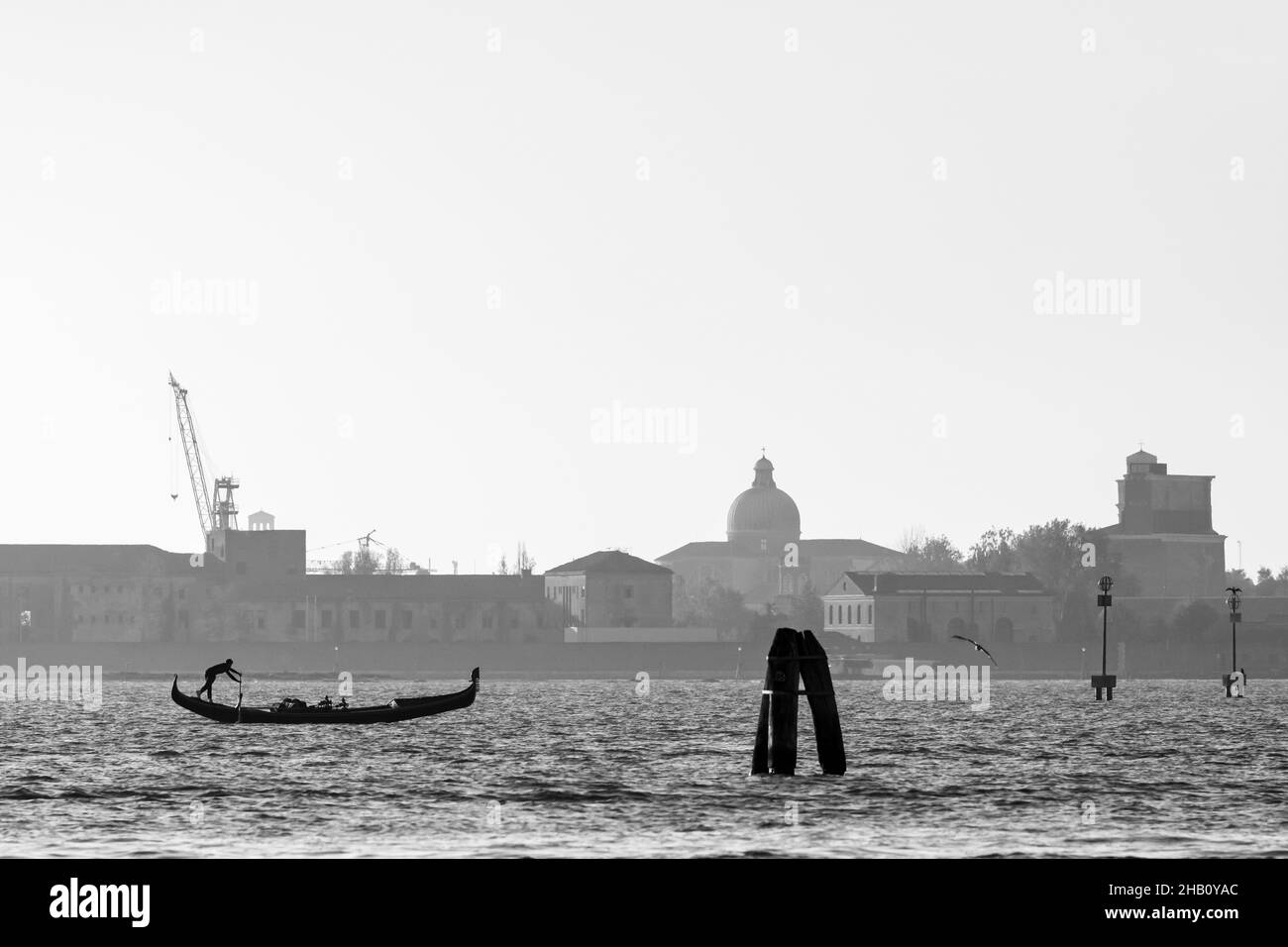 Venise, Italie - 29 octobre 2021 : homme rasant une gondole dans la lagune de Venise (Italie) par une journée ensoleillée en hiver Banque D'Images