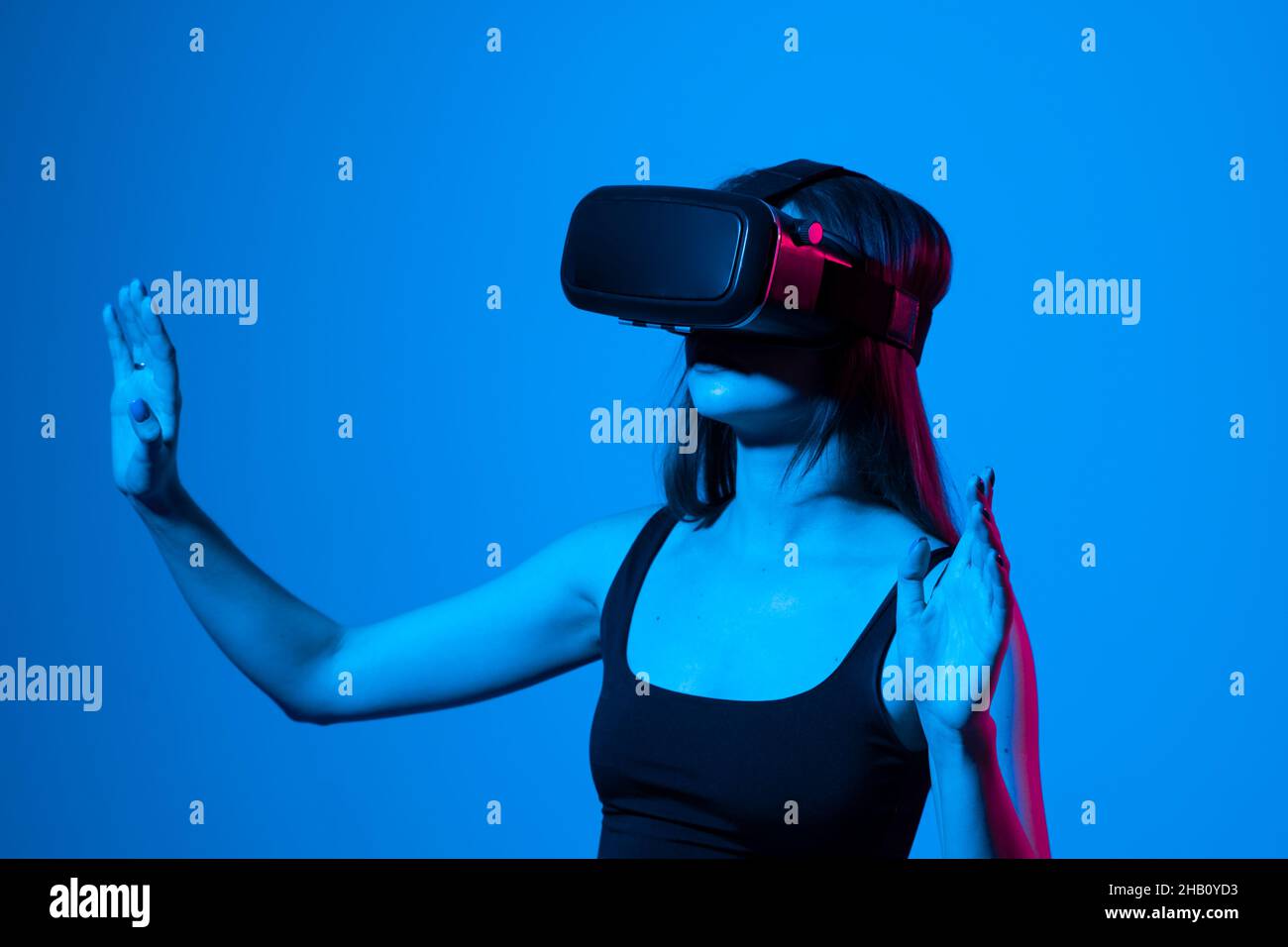 Jeune femme utilisant un casque VR pour interagir avec un métaverse en utilisant des gestes de glissement et d'étirement.Regarder des vidéos 3d de réalité virtuelle.Fille en VR Banque D'Images