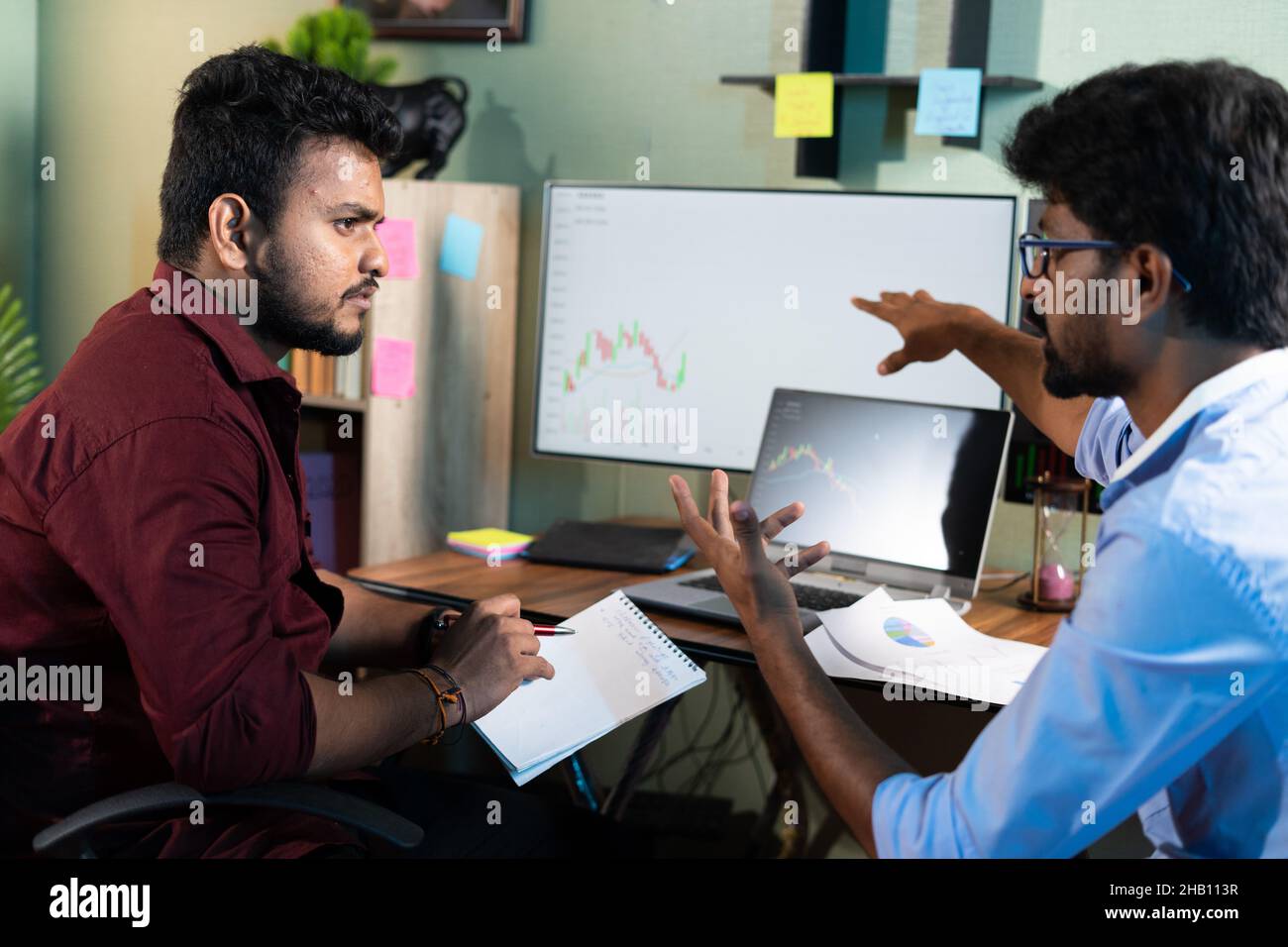 Les traders analysent en discutant des graphiques boursiers tout en travaillant au bureau - concept de travail d'équipe, d'apprentissage ou de planification stratégie de marché de partage Banque D'Images