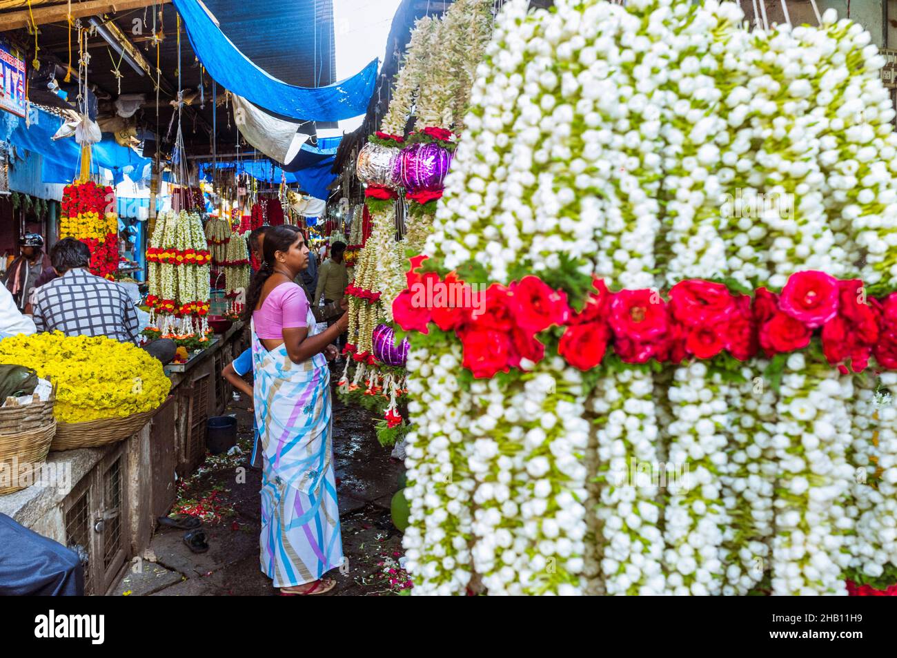 Mysore, Karnataka, Inde : Une femme fait des magasins de guirlandes de fleurs au marché de Devaraja. Banque D'Images