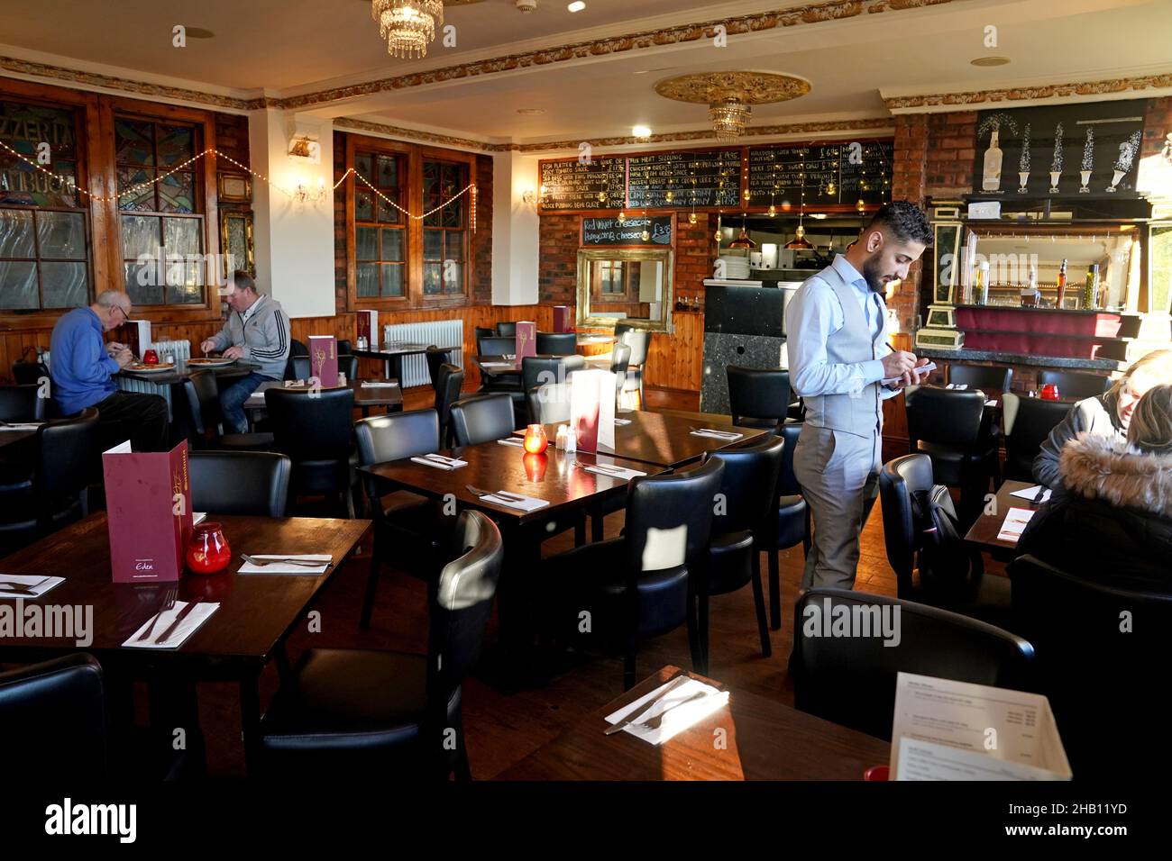 Un serveur prend les commandes de deux clients dans le restaurant quasi vide Cassia Sambuca à North Shields, North Tyneside, qui serait normalement emballé avec des clients profitant des offres spéciales du déjeuner.Les entreprises d'accueil augmentent les demandes de soutien du gouvernement pour des pubs et des restaurants à succès tandis que la variante d'Omicron balaie le pays et que la confiance des consommateurs est ébranlées par de nouvelles restrictions et des avertissements sanitaires croissants.Date de la photo: Jeudi 16 décembre 2021. Banque D'Images