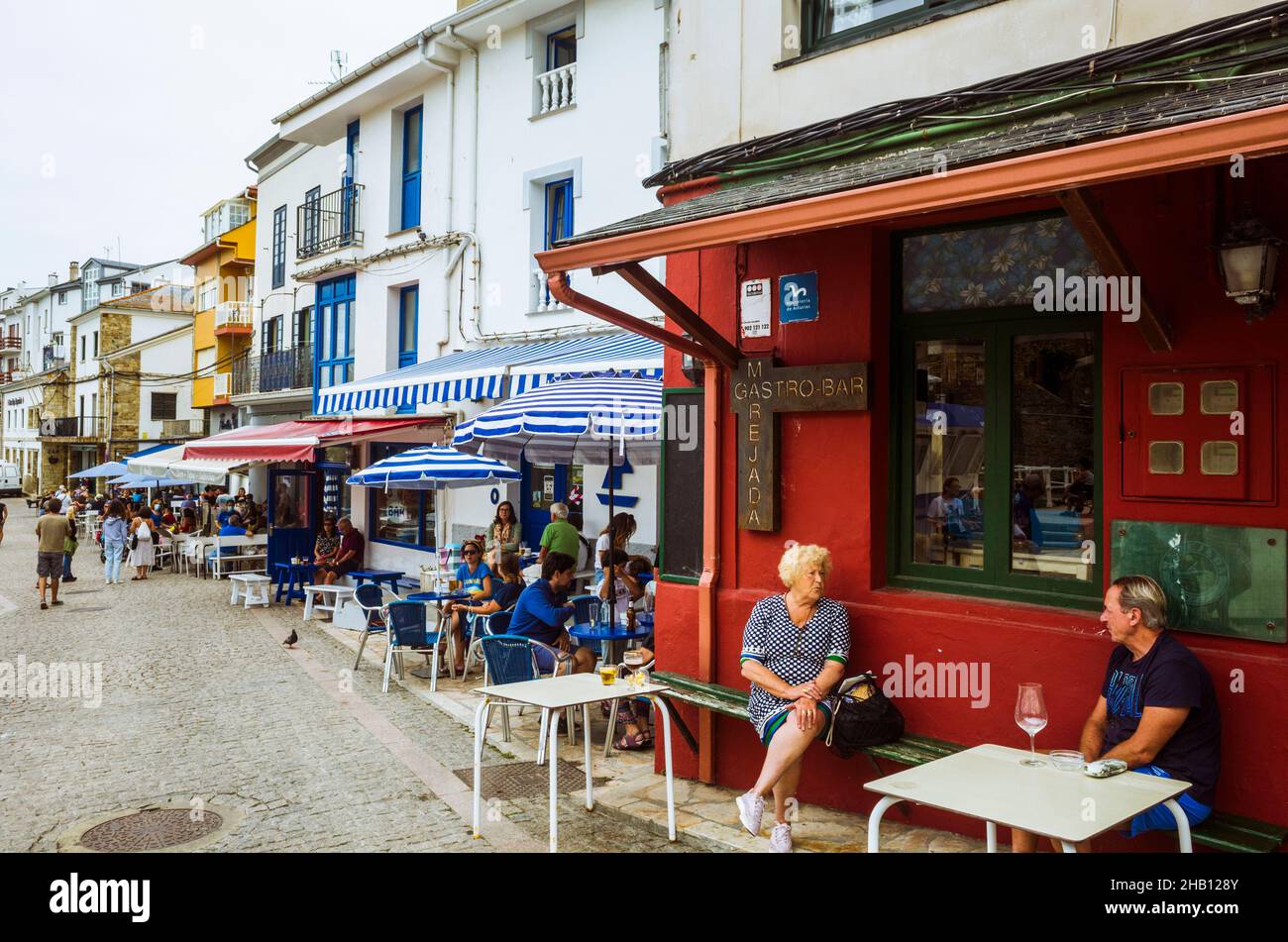 Tapia de Casariego, Asturies, Espagne : Un homme et une femme bavarde dans un café en plein air dans le port de pêche. Banque D'Images