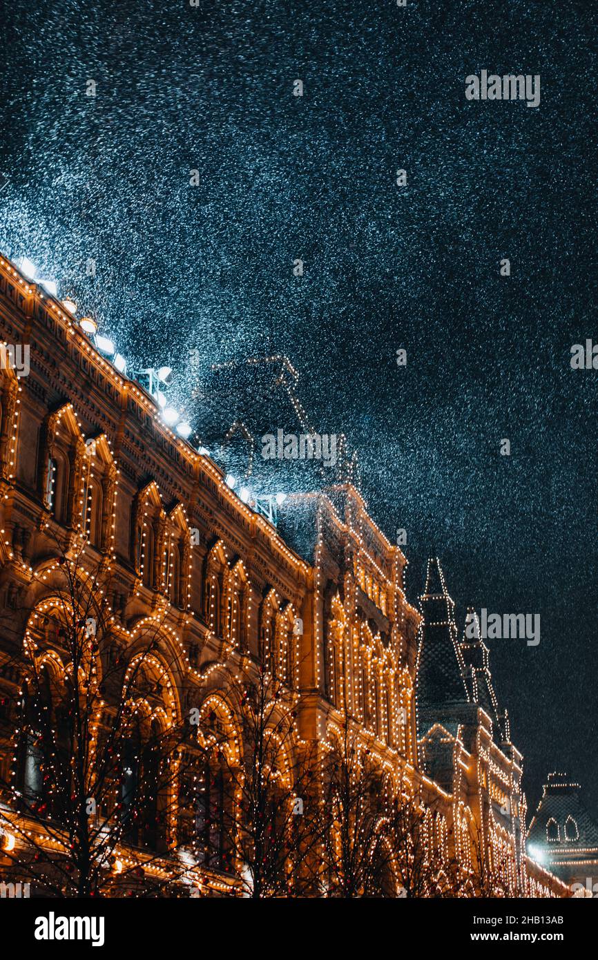 Neige magique volant dans la lumière du soir au-dessus d'un bâtiment d'époque doré lumineux.Architecture européenne.Atmosphère de fée d'hiver Banque D'Images