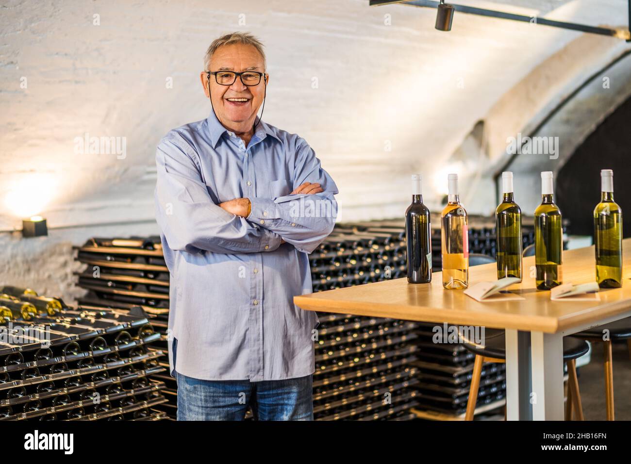 Portrait d'un homme senior heureux qui possède un domaine viticole.Il est debout dans sa cave à vin.Industrie du vin concept. Banque D'Images