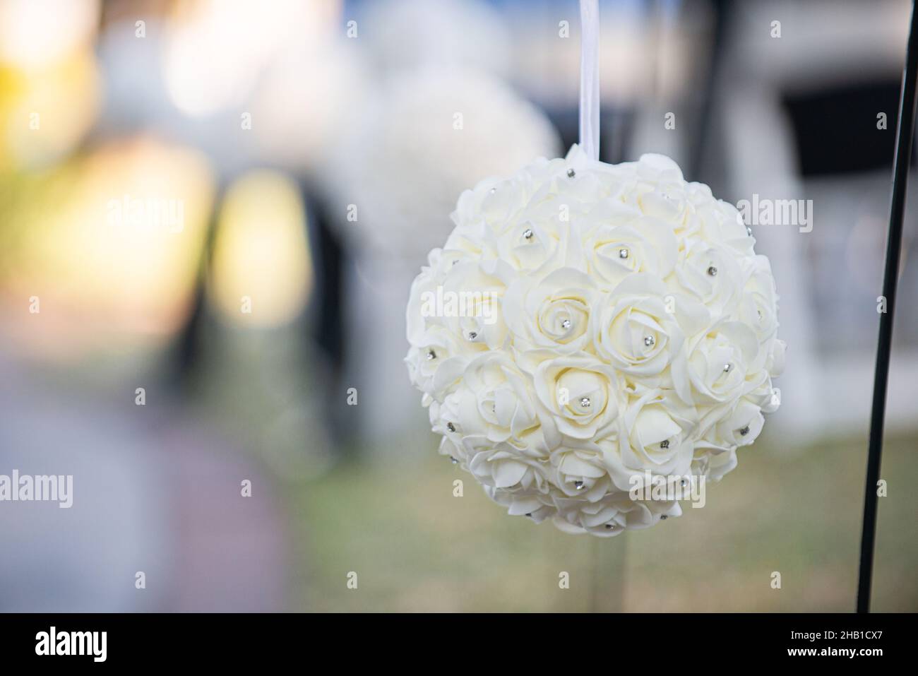 Boule de fleurs blanches avec décoration de diamants accrochée à l'isle lors d'une cérémonie de mariage en plein air Banque D'Images