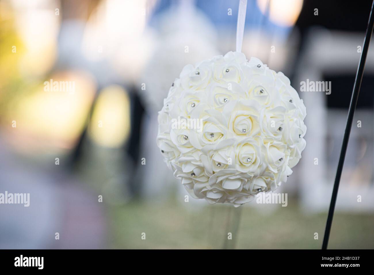 Boule de fleurs blanches avec décoration de diamants accrochée à l'isle lors d'une cérémonie de mariage en plein air Banque D'Images