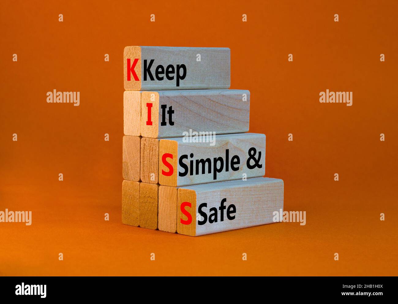 SYMBOLE KISS Keep IT simple and safe.Les mots de concept KISS permettent de garder des blocs de bois simples et sûrs.Belle table orange, fond orange.Entreprise et Banque D'Images