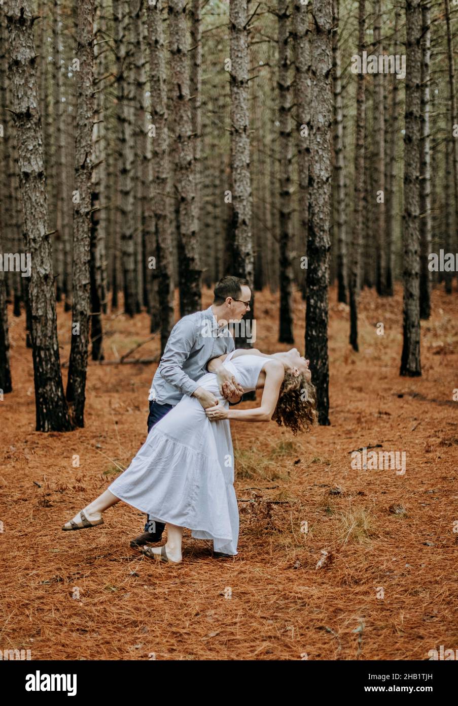 L'homme danse et plonge la femme en robe blanche dans la forêt de pins, Michigan Banque D'Images