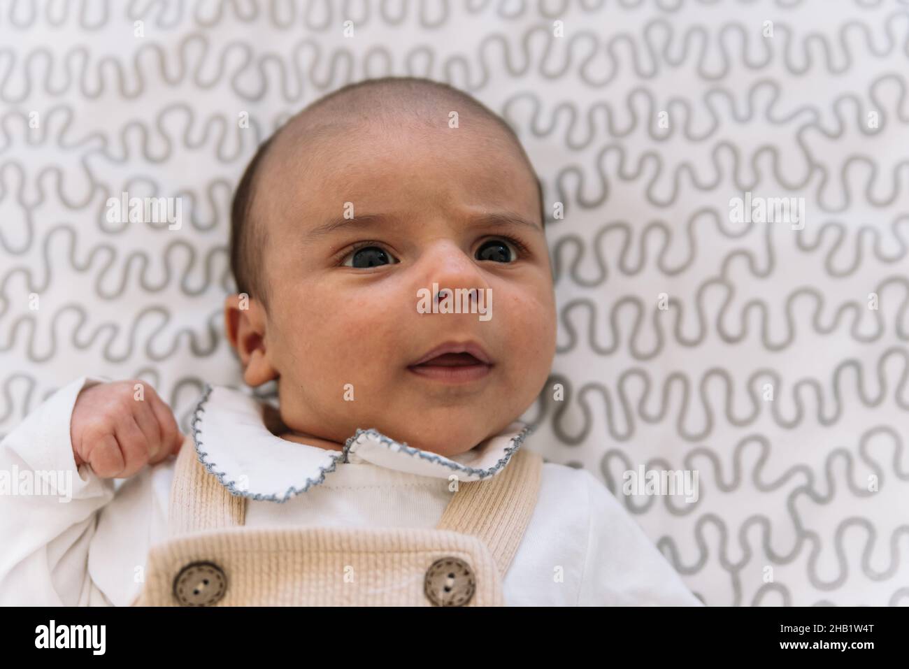 Bébé élégant en costume et salopette couchée sur le lit. Banque D'Images